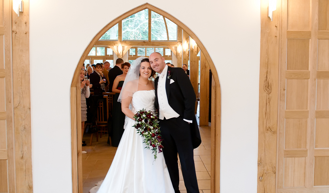 the newlywedded couple posed outside the Ceremony Barn at their barn wedding venue in Hampshire