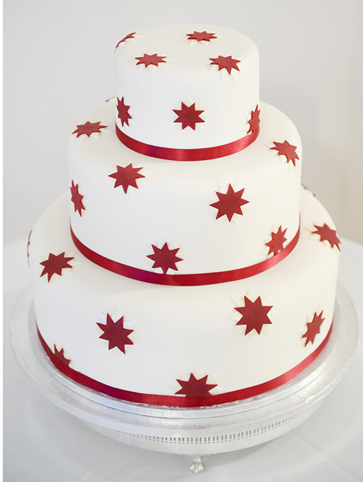 The three-tiered cake was decorated with red ribbon and red starts to match their winter wedding inspired day