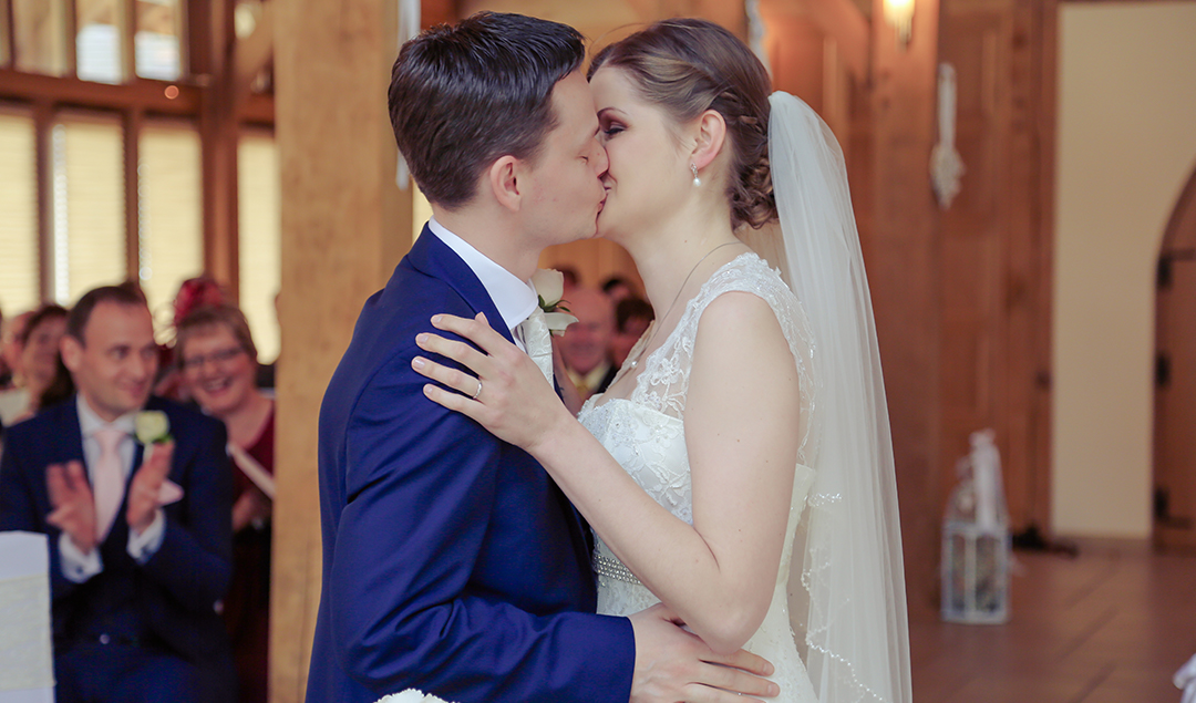 Jen and James share a kiss in the Ceremony Barn at one of Hampshire’s finest wedding venues
