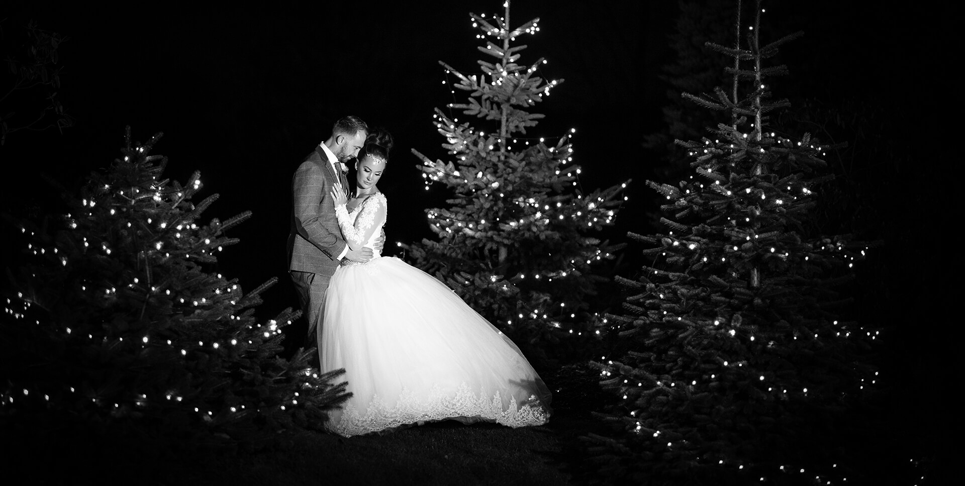 The bride and groom posed between Christmas trees for their winter themed evening reception