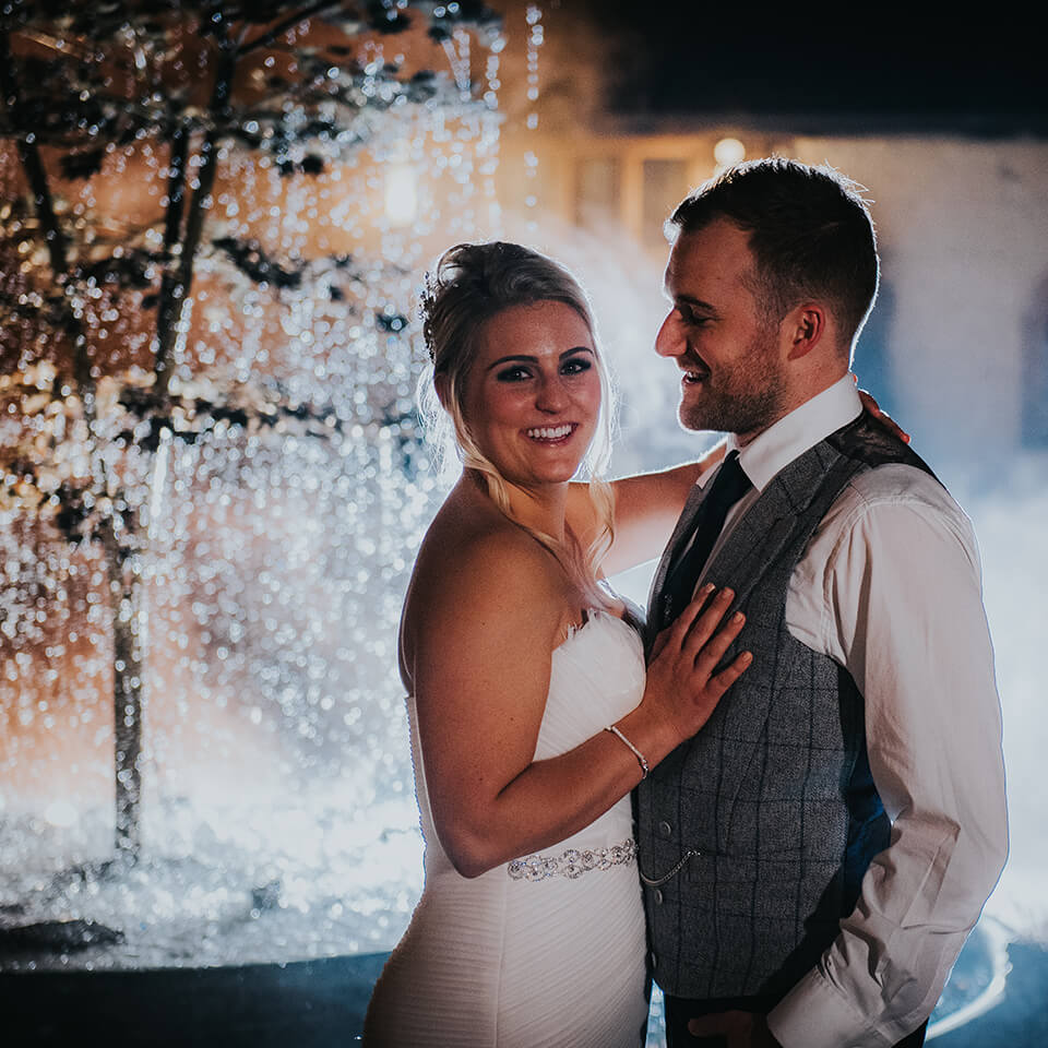 Michelle and Chris pose in front of the beautiful water feature at their beautiful wedding venue in Hampshire