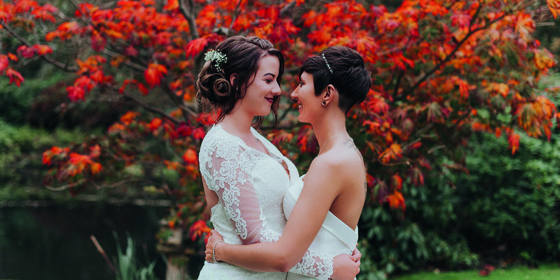 The brides pose in front of autumn leaves at this beautiful Hampshire wedding venue