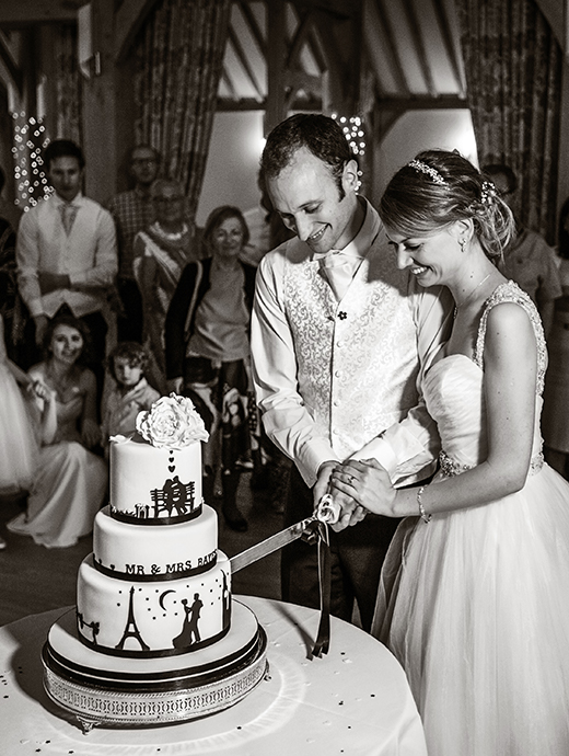 The newlyweds cut into their tiered wedding cake at this stunning barn venue in Hampshire