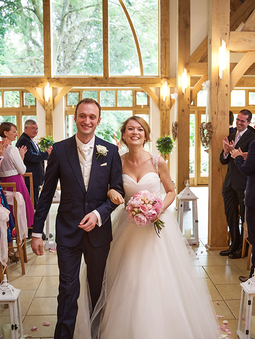Nikki and Maurice leave the ceremony barn arm in arm after a stunning ceremony at one of Hampshire’s most exquisite wedding venues
