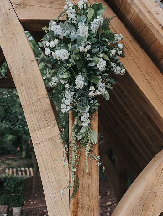 elegant white bouquets hang from Rivervale Barn’s outdoor wedding ceremony space, The Spinney