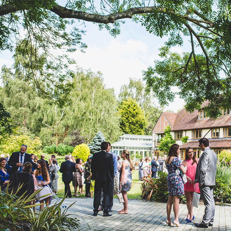 Wedding guests gather outside the beautiful gardens of this barn wedding venue in Hampshire