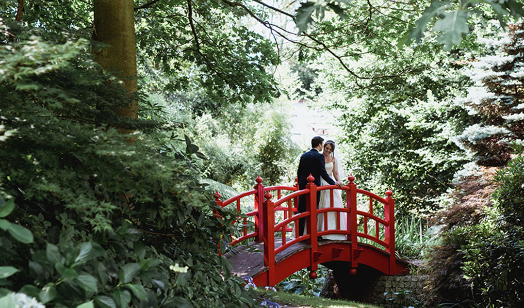 The bright Japanese bridge stands out in the gardens of this barn wedding venue in Hampshire