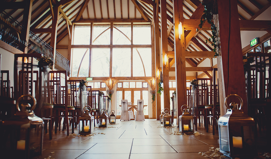 The ceremony barn decorated with lanterns down the aisle ready for the bride