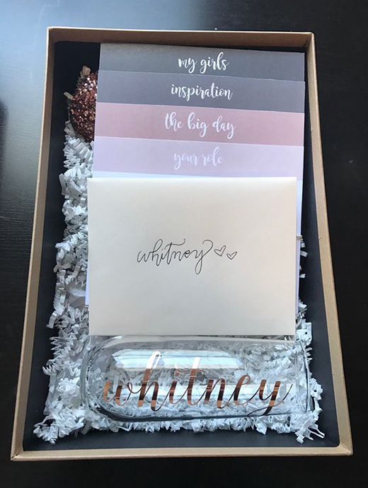A bridesmaid proposal box filled with handwritten cards and a personalised glass ready for toasting