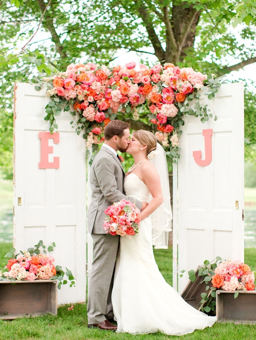 a bride and groom share a kiss in front of a coral coloured tree