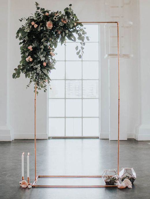 A modern take on wedding arches with a metal frame and overgrown bloom