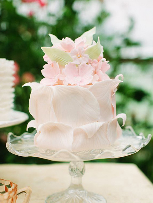A beautifully decorated summer themed wedding cake in blush and green
