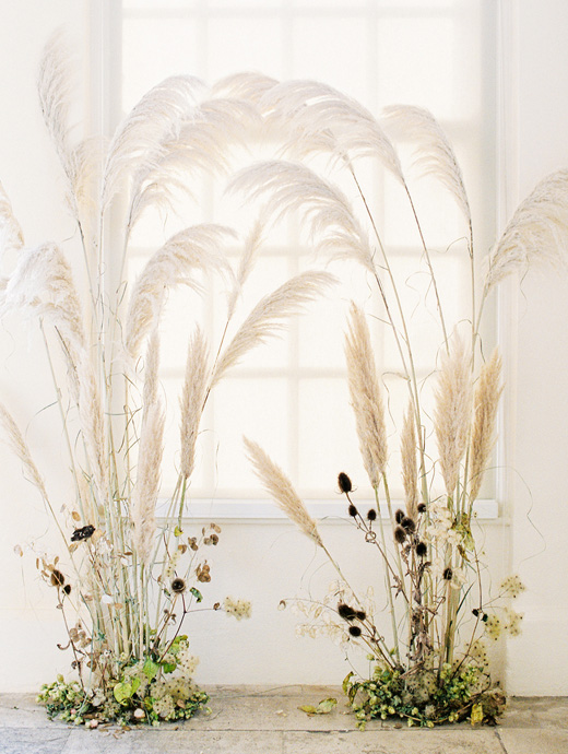 a unique version of a wedding arch made from long grass and delicate flowers