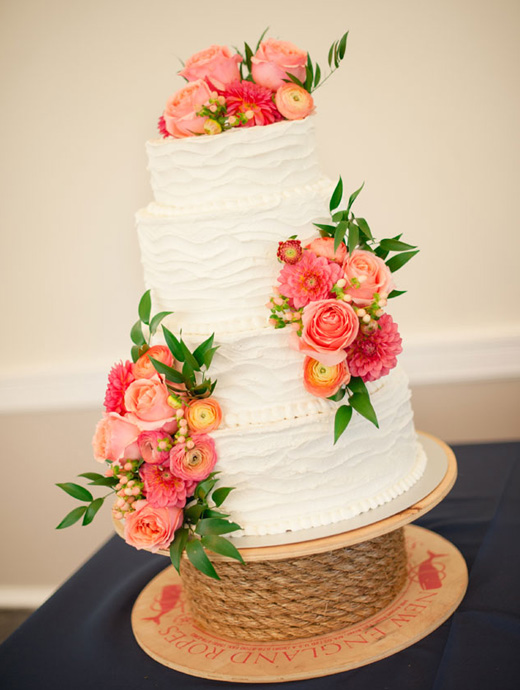 a stunning white wedding cake decorated with coral blooms