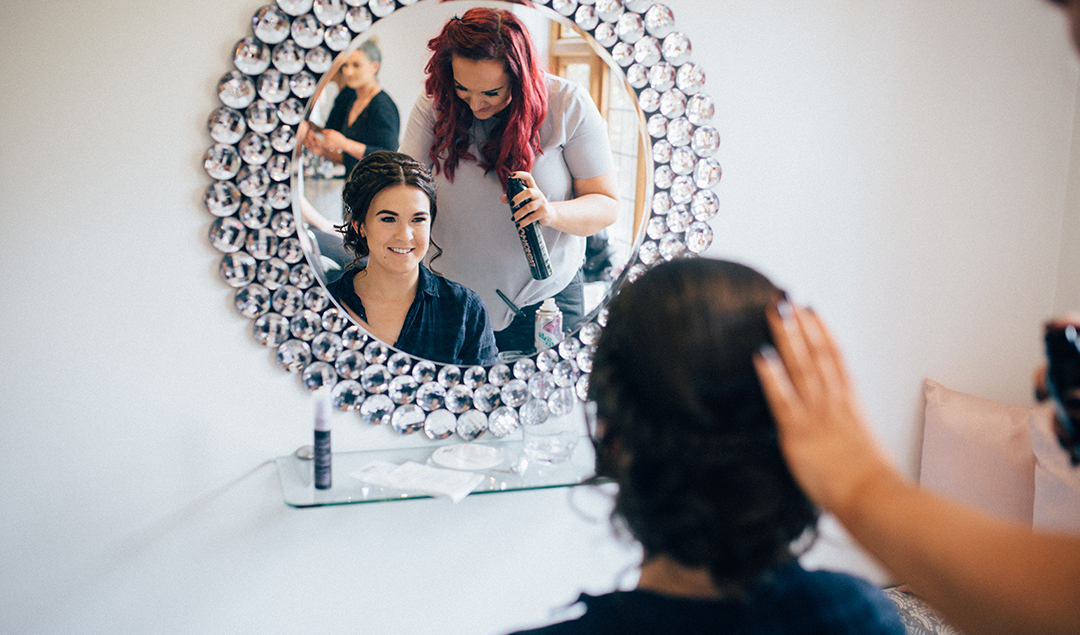 the bride having her hair done in Rivervale Barn’s bridal preparation room before her wedding ceremony