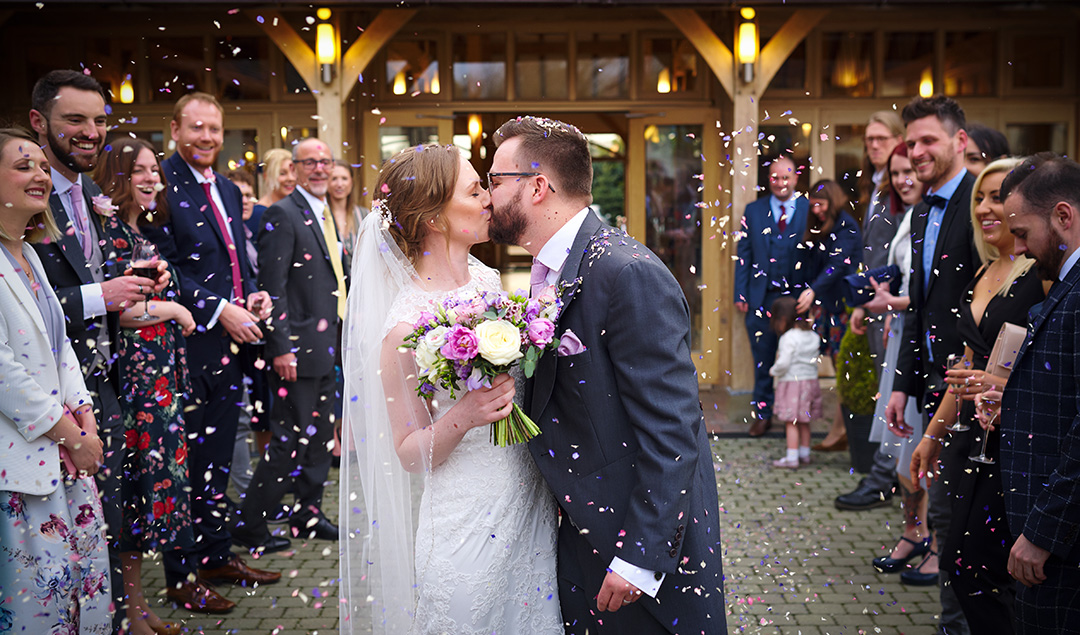 Guests throw confetti in the courtyard at the happy newlyweds
